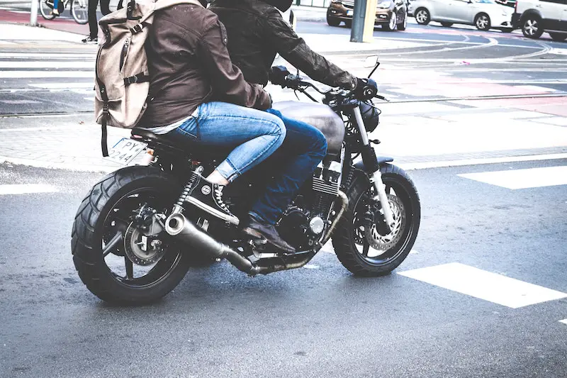passenger wearing backpack on motorcycle
